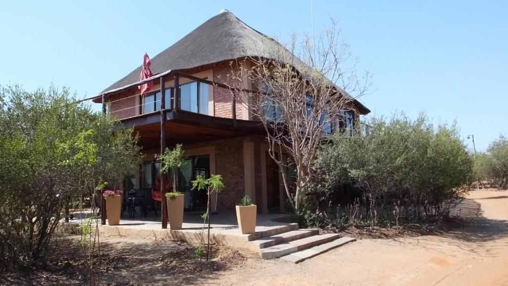 a thatch roofed house with a thatched roof at Baobab - NUDE - SunEden Family Naturist Resort in Pretoria