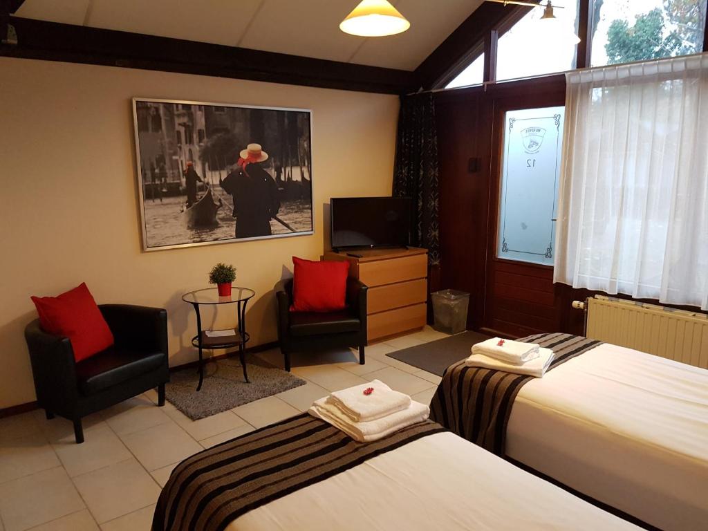 a hotel room with two beds and two chairs and a television at Motel Oostvoorne in Oostvoorne