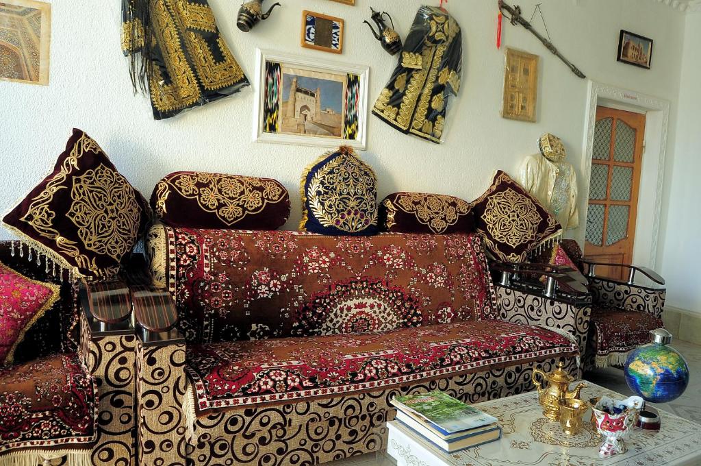 een woonkamer met een rode bank en veel kussens bij Khan Rooms in Bukhara
