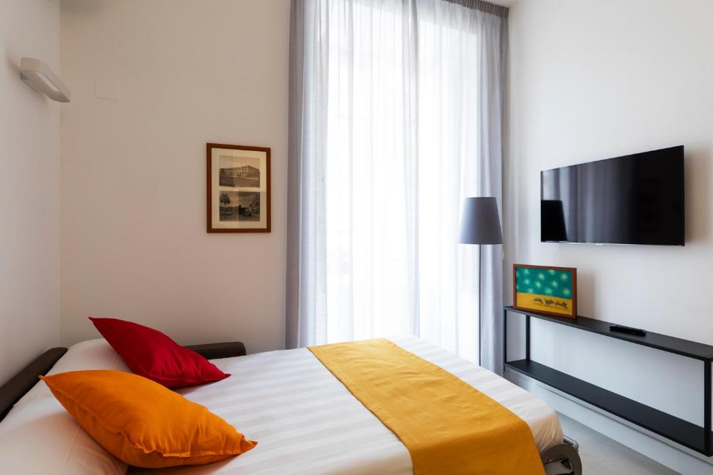 a bedroom with a bed with orange pillows and a flat screen tv at Acate81 Lifestyle Apartment in Naples