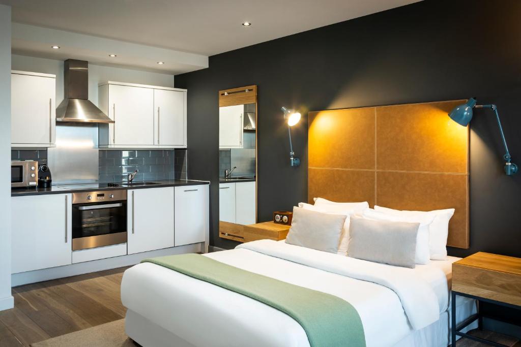 Aparthotel Adagio London Brentford في برينتفورد: غرفة نوم بسرير كبير ومطبخ
