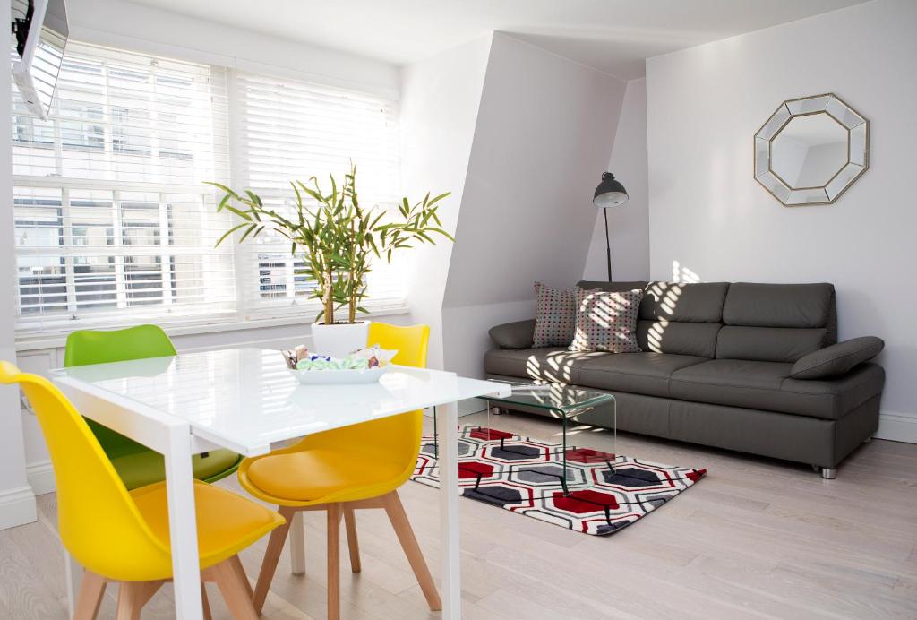 sala de estar con mesa blanca y sillas amarillas en Soho Chambers by Indigo Flats, en Londres