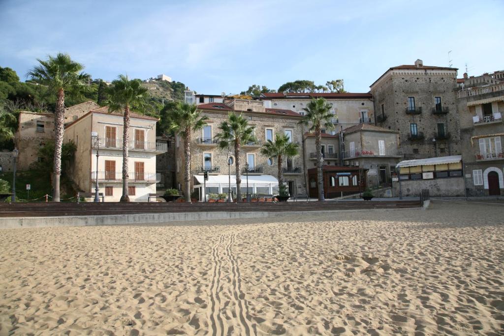 a beach in front of some buildings and palm trees at Palazzetto Florio 1810 in Santa Maria di Castellabate