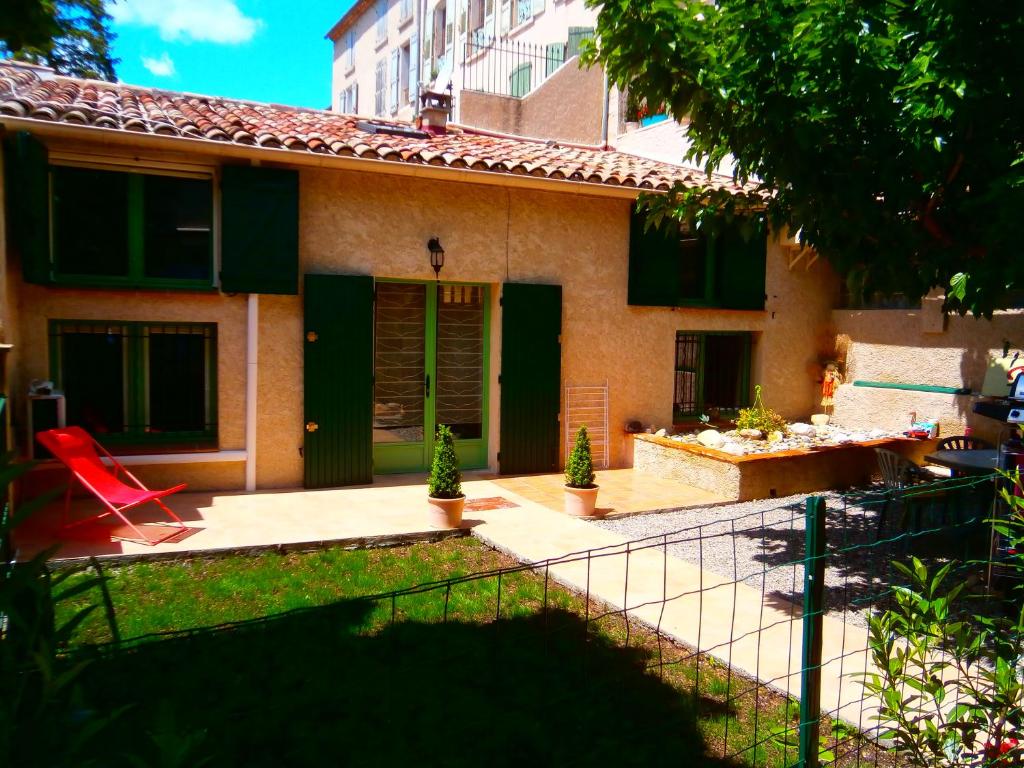 une maison avec une chaise rouge dans la cour dans l'établissement ic locations, à Riez