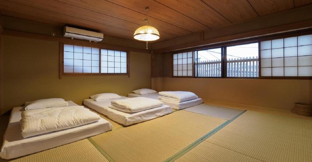 a bedroom with three beds in a room with windows at Kyoto Hostel japanese room 3F / Vacation STAY 8183 in Kyoto