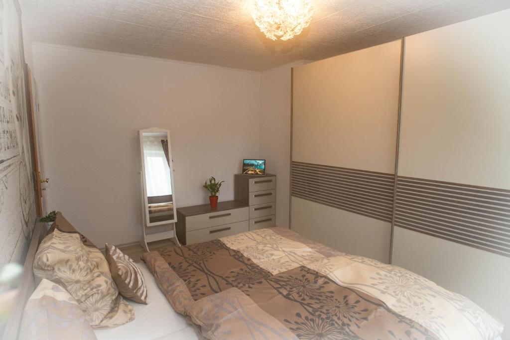 1 dormitorio con cama, tocador y espejo en FeWo Fam. Groß en Sehma