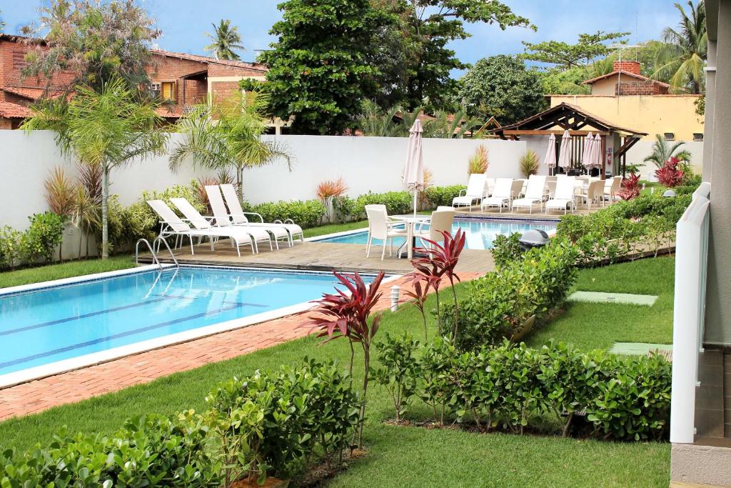 a backyard with a swimming pool and lawn with lounge chairs at Porto Plaza Flat Porto de Galinhas in Porto De Galinhas
