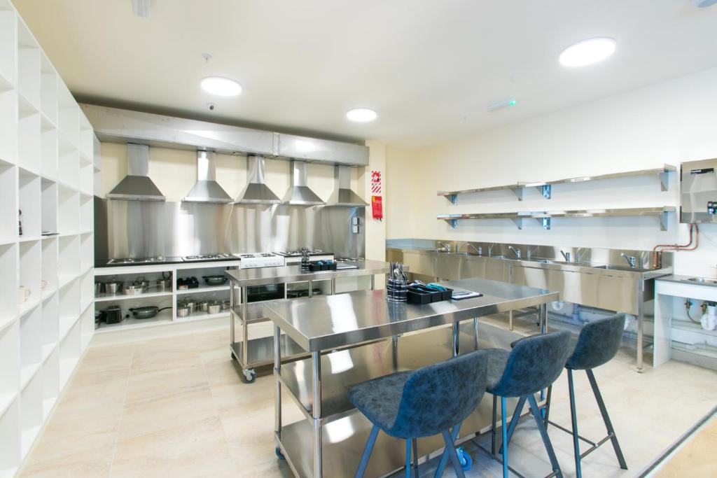 una grande cucina con tavoli in acciaio inossidabile e sedie blu di Hobson Lodge ad Auckland