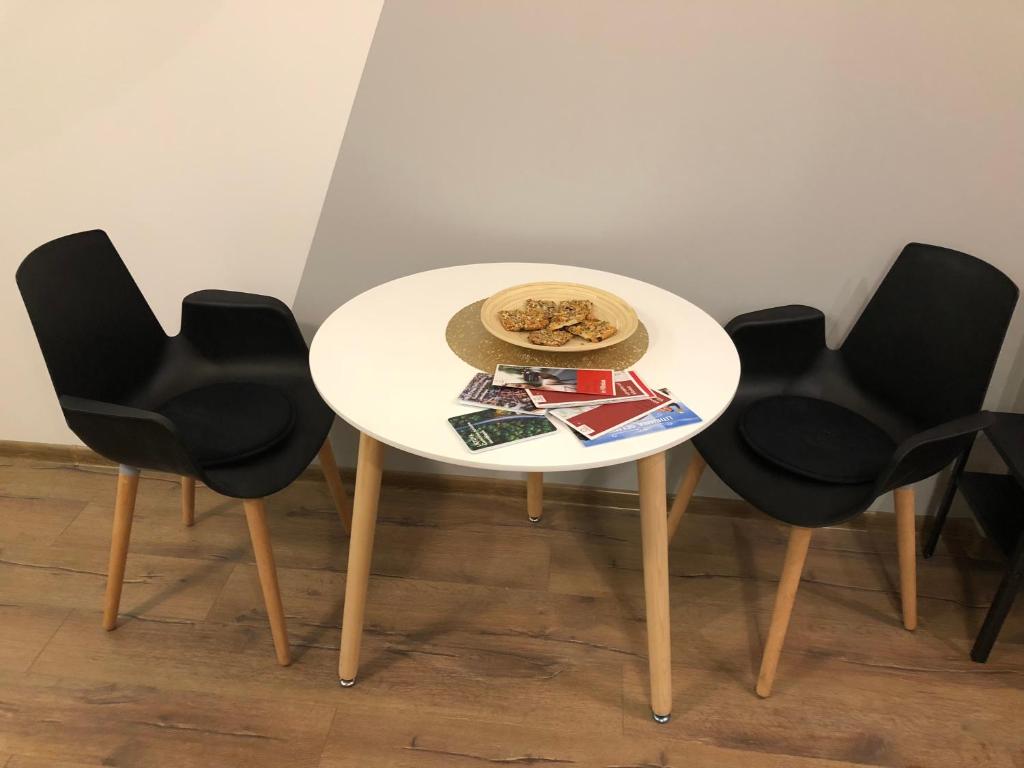 een witte tafel met zwarte stoelen en een hoed erop bij K&P Apartment in Vilnius