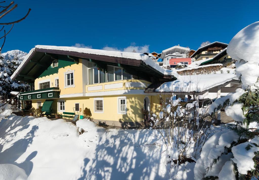 a yellow house in the snow with snow covered trees at Apartment Lausbuam in Mühlbach am Hochkönig