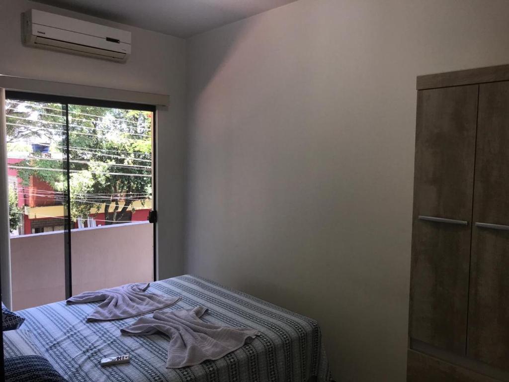 a bedroom with a bed and a window at Suite Cardoso in Foz do Iguaçu