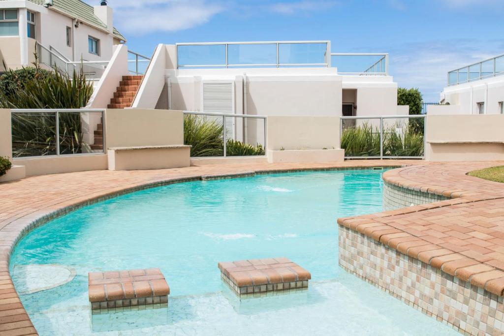 a swimming pool in front of a house at Modern Seaview Apartment in Summerstrand