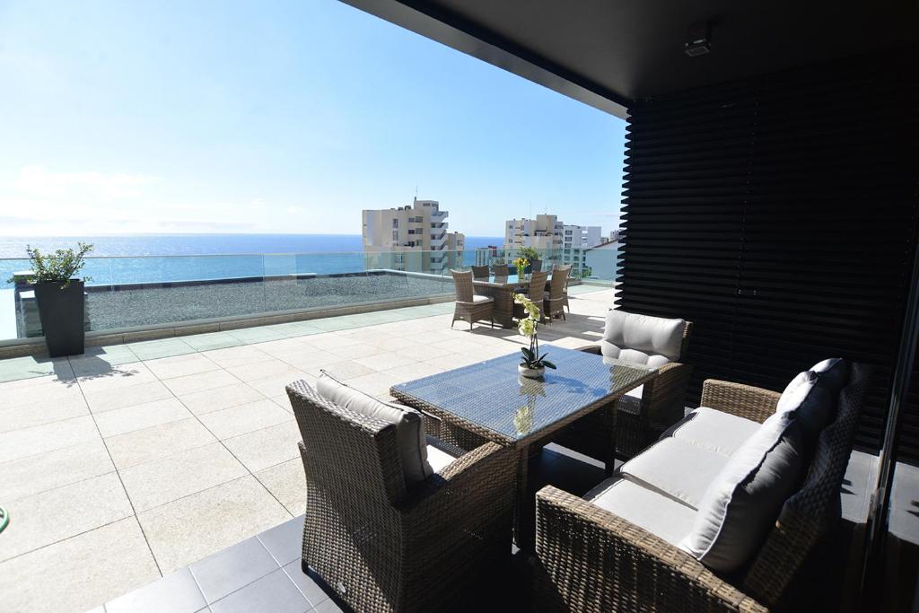 een patio met een tafel en stoelen en de oceaan bij Sec XXI 12 - 3 Bed Flat in Funchal
