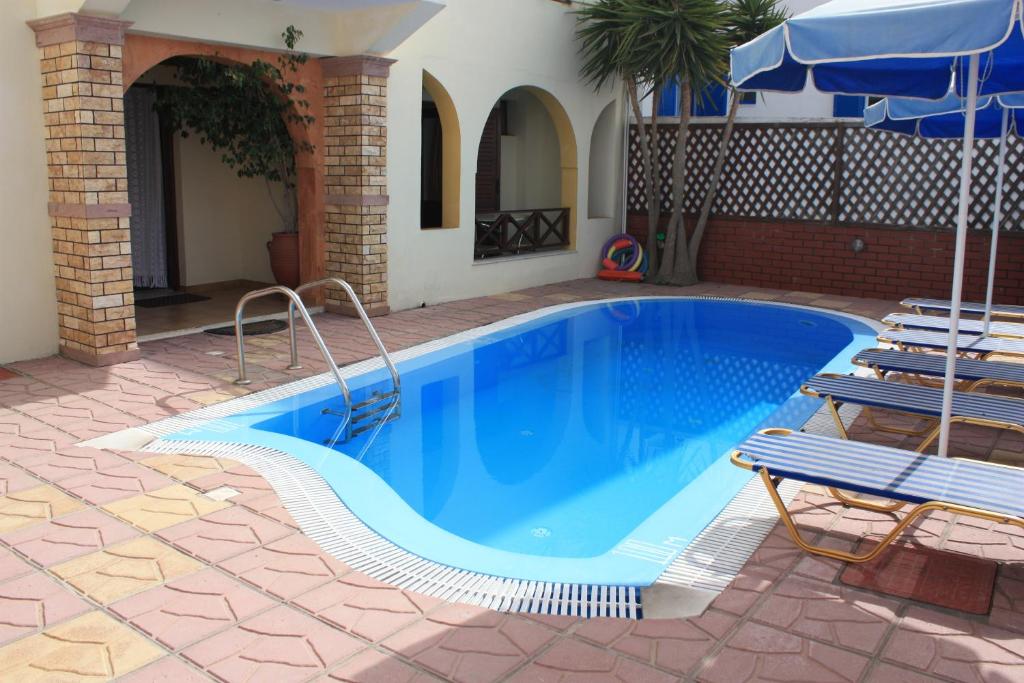 basen z 2 krzesłami i parasolem w obiekcie Pension Stella w mieście Karterados