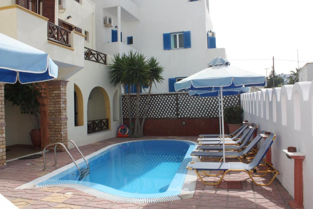 - une piscine avec des chaises et des parasols à côté d'un bâtiment dans l'établissement Pension Stella, à Karterados