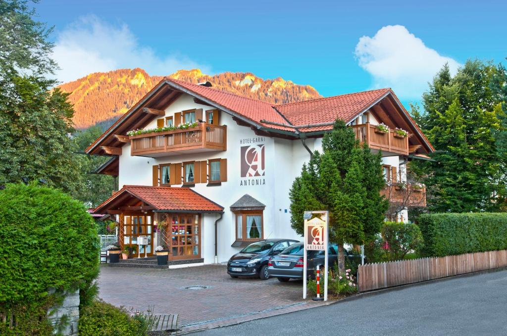 een gebouw waar auto's voor geparkeerd staan bij Hotel Antonia in Oberammergau