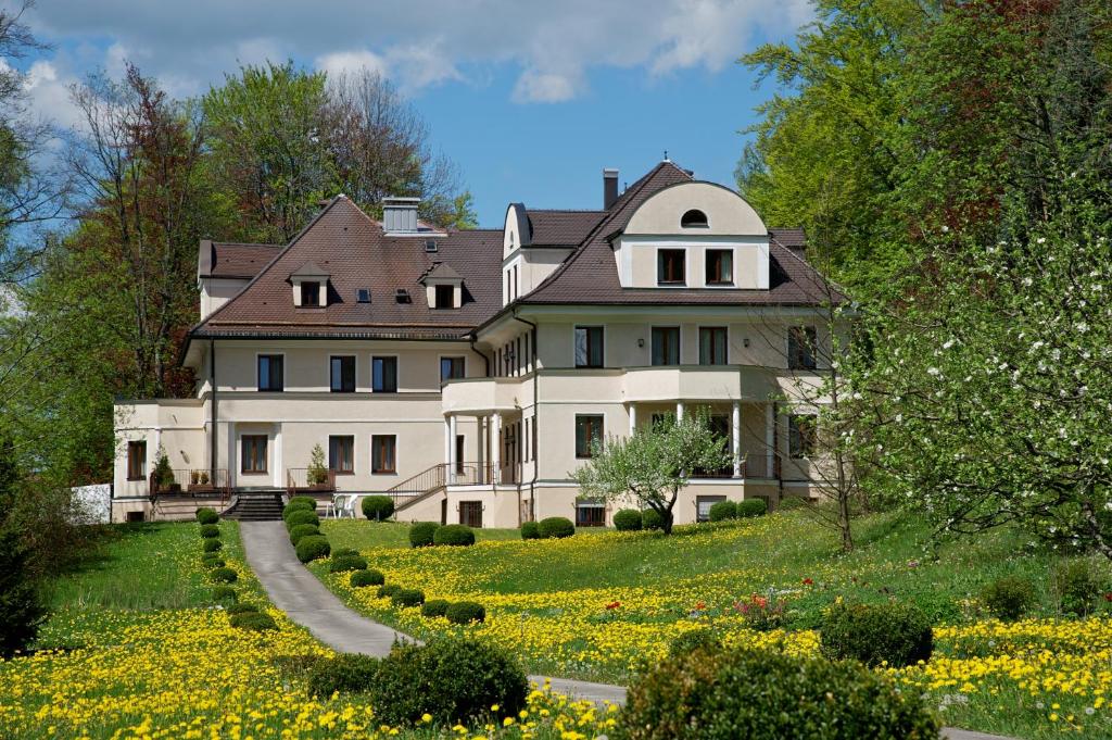 ein großes weißes Haus auf einem Hügel mit Blumen in der Unterkunft hideauts hotels Der Rosengarten in Füssen
