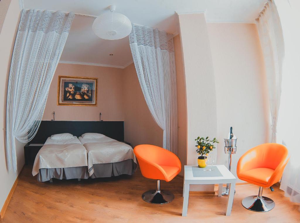 a bedroom with a bed and two orange chairs at Cruise Hotel in Pionerskiy
