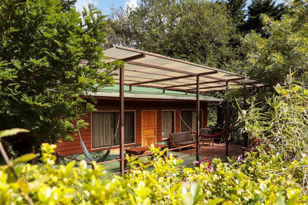 a cottage with a deck with a pergola at Los Pinos Cabins & Reserve in Monteverde Costa Rica