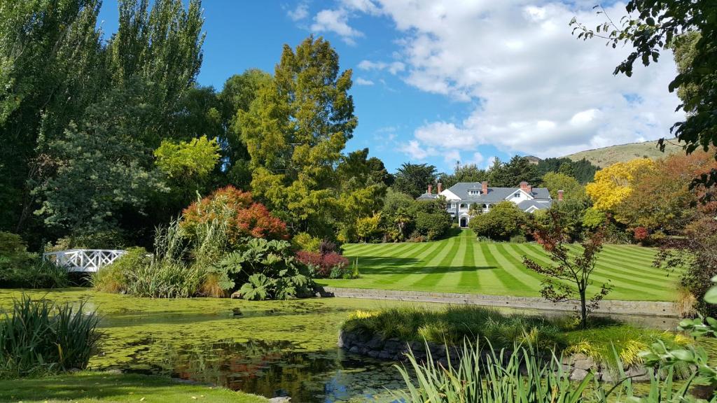 a garden with a pond in front of a house at Otahuna Lodge in Christchurch