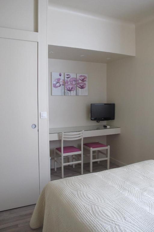 a bedroom with a bed and a desk with a television at Hotel Le Havre Bleu in Beaulieu-sur-Mer