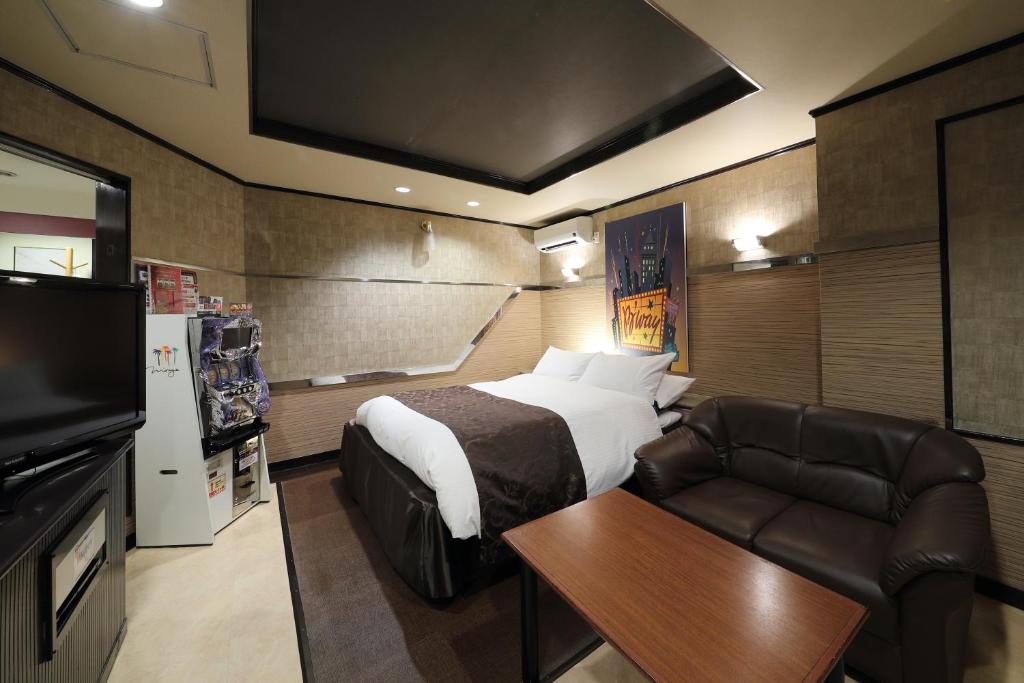 a bedroom with a bed and a couch and a television at Hotel Fine Garden Okayama II in Okayama