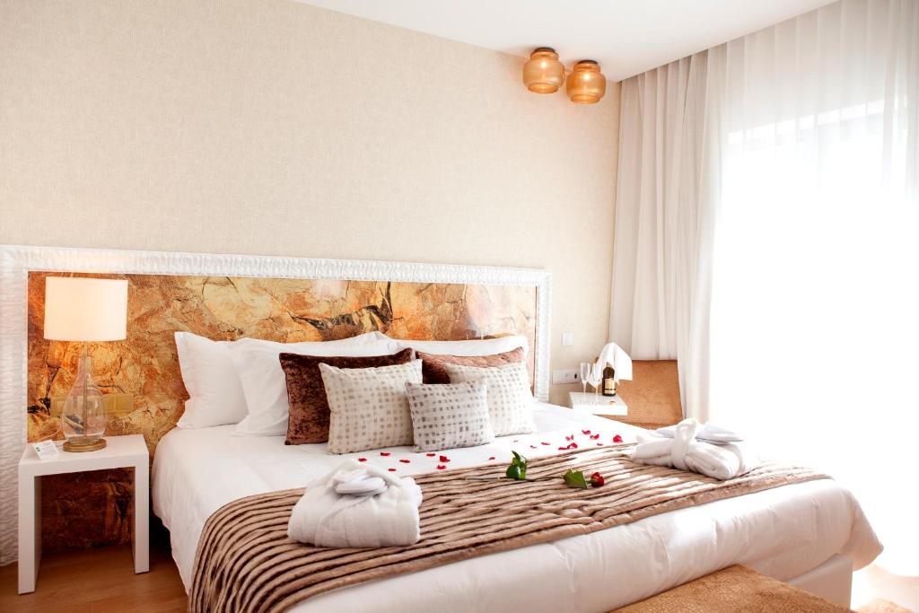 Flag Hotel Villa Aljustrel في الجوسترل: غرفة نوم بسرير ابيض كبير عليها ورد