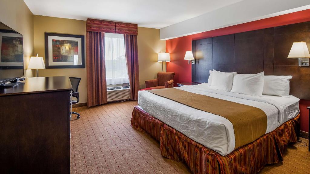 a hotel room with a large bed and a desk at Best Western Plus Bowmanville in Bowmanville