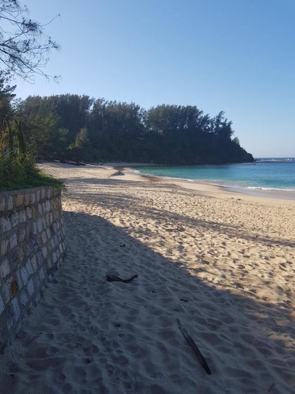 einen Sandstrand mit einer Wand und dem Meer in der Unterkunft Villa océane in Tôlagnaro