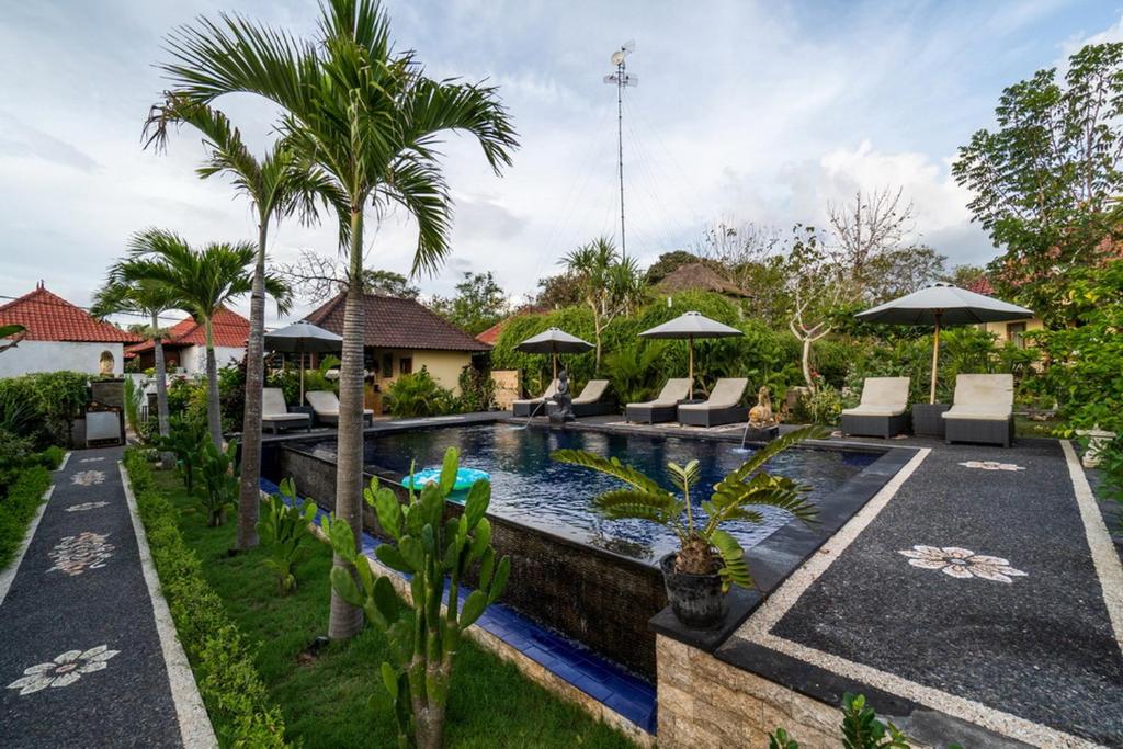 a pool with chairs and umbrellas in a backyard at Sunset Cave Villas Lembongan in Nusa Lembongan