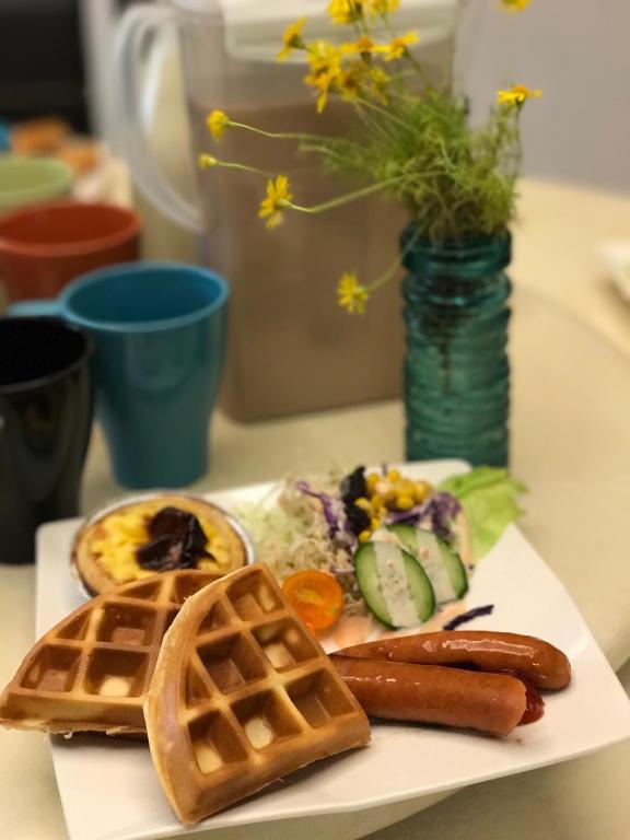 a plate of breakfast food with sausage and waffles at Yurong B&amp;B in Magong