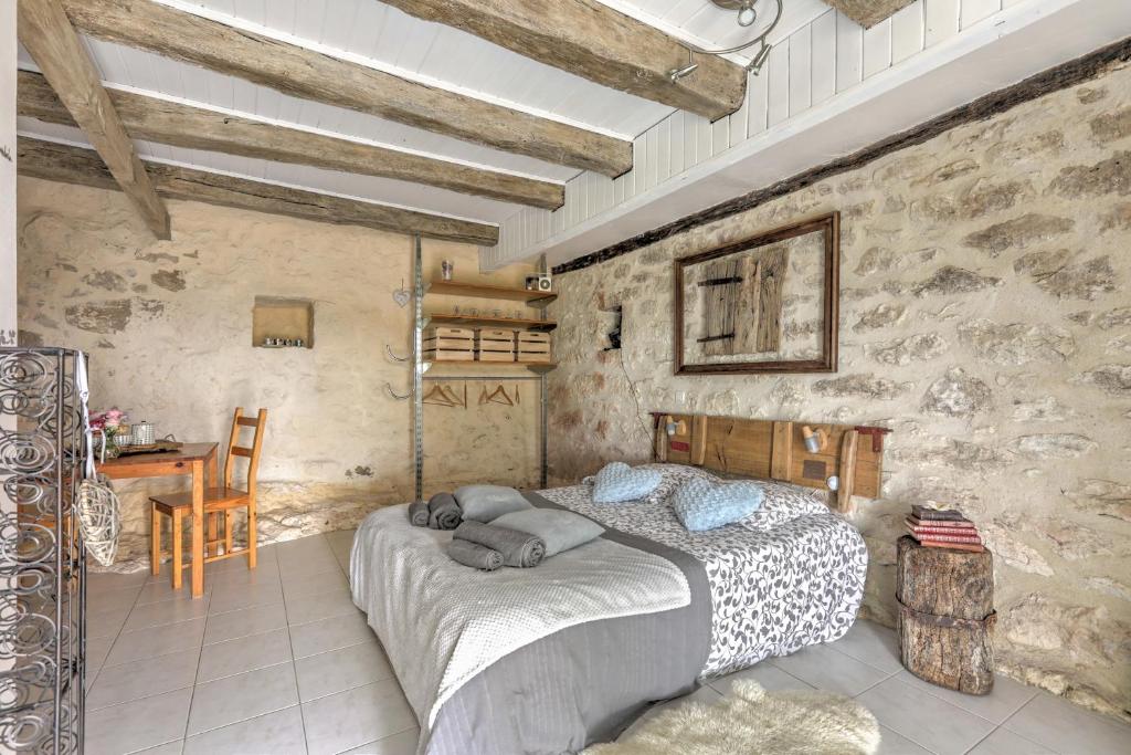 ein Schlafzimmer mit einem großen Bett in einer Steinmauer in der Unterkunft Le Mas des Papillons in Fargues