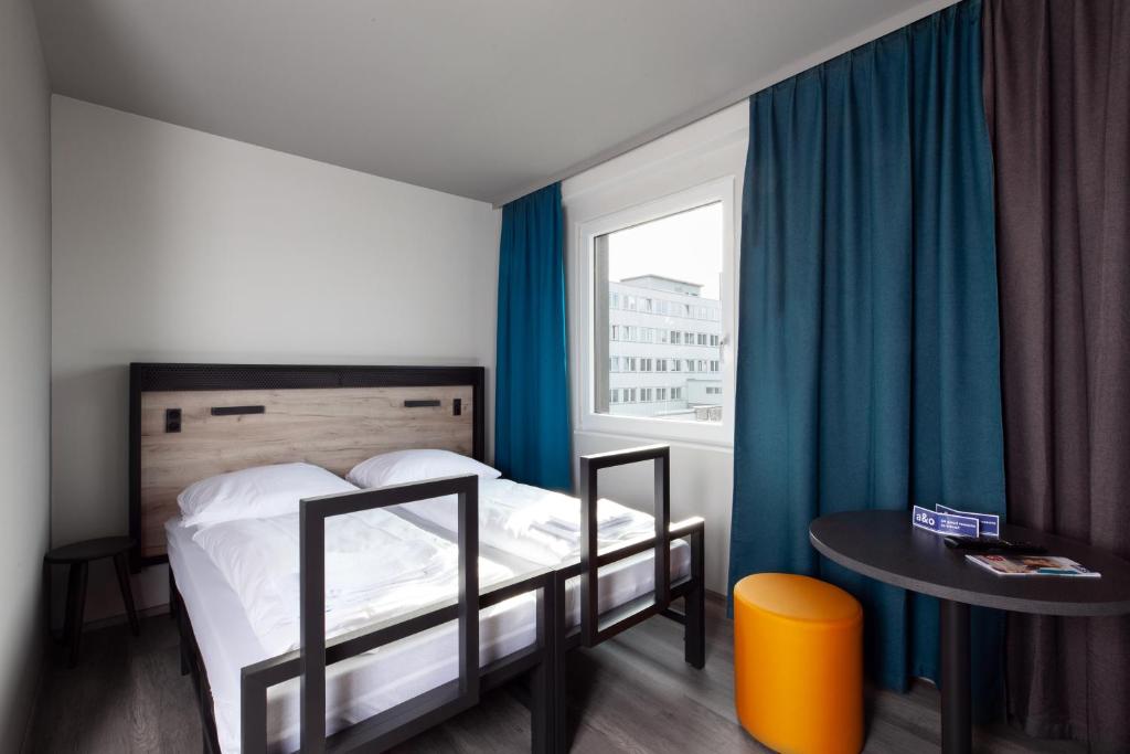 a bedroom with a bed and a table and a window at a&o Frankfurt Ostend in Frankfurt/Main