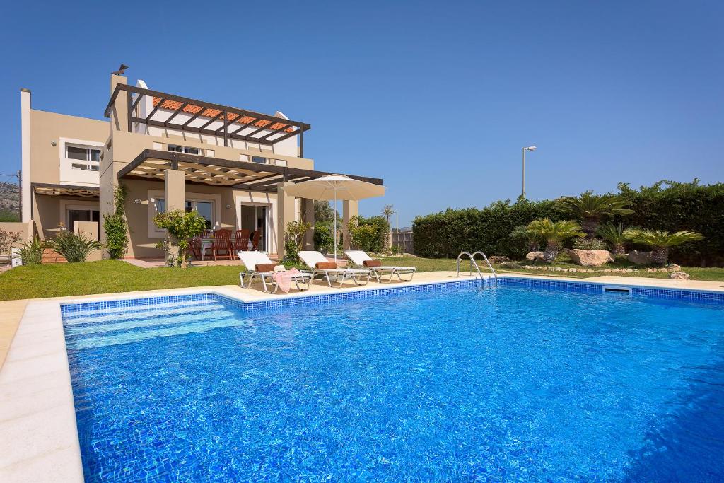a villa with a swimming pool in front of a house at Evergreen Seaside Villa with private pool in Faliraki