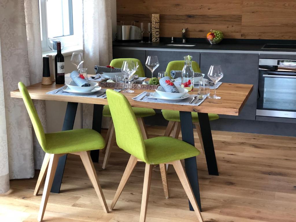 Am Holzmeisterweg 31 "Erika" في غوساو: طاولة غرفة الطعام مع كراسي خضراء وكؤوس للنبيذ