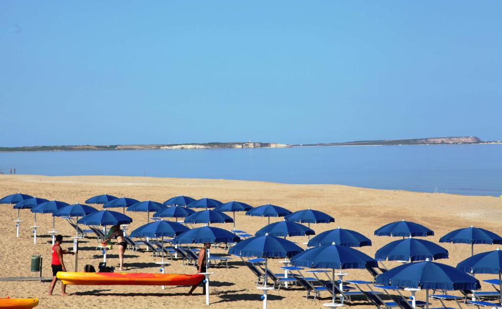 - un groupe de parasols et de chaises bleus sur une plage dans l'établissement Happy Camp mobile homes in Camping Village Bella Sardinia, à S'archittu Cuglieri
