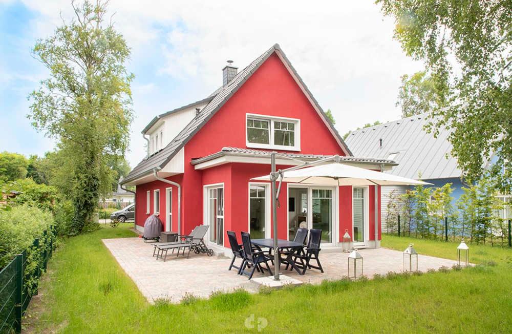 uma casa vermelha com uma mesa e cadeiras no quintal em Ferienhaus ELSA Kinder erst ab 12 em Dierhagen