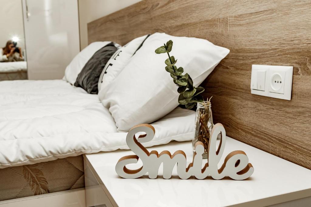 リヴィウにあるLoft apartmentのベッド横のテーブルに笑顔を添える看板