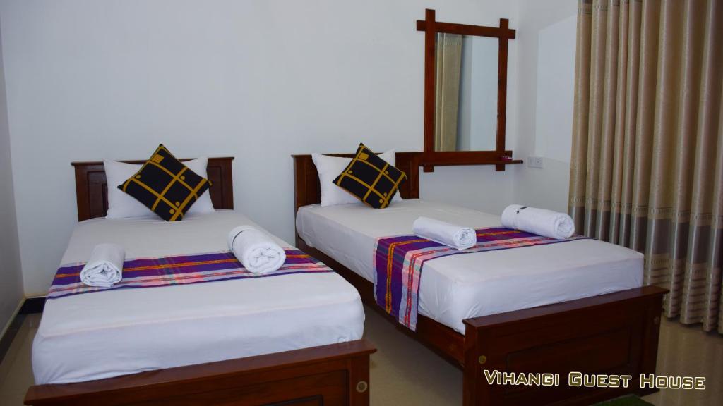 Vihangi Guesthouse في دامبولا: غرفة نوم بسريرين مع شراشف بيضاء