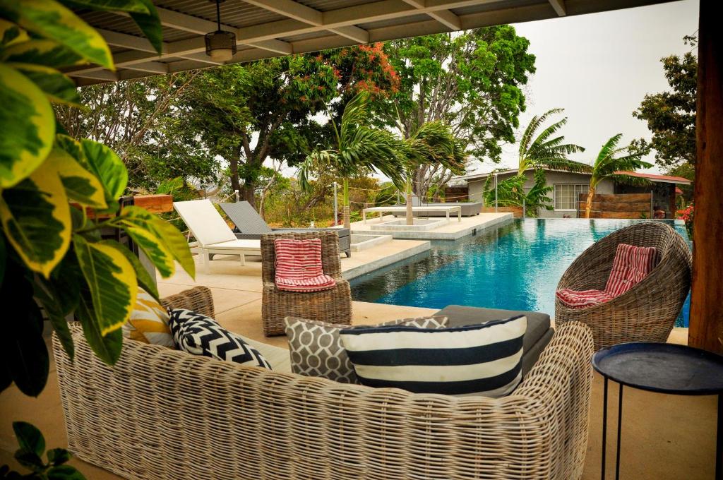 eine Terrasse mit Korbstühlen und einem Pool in der Unterkunft La Maracuya Panama in Playa Coronado