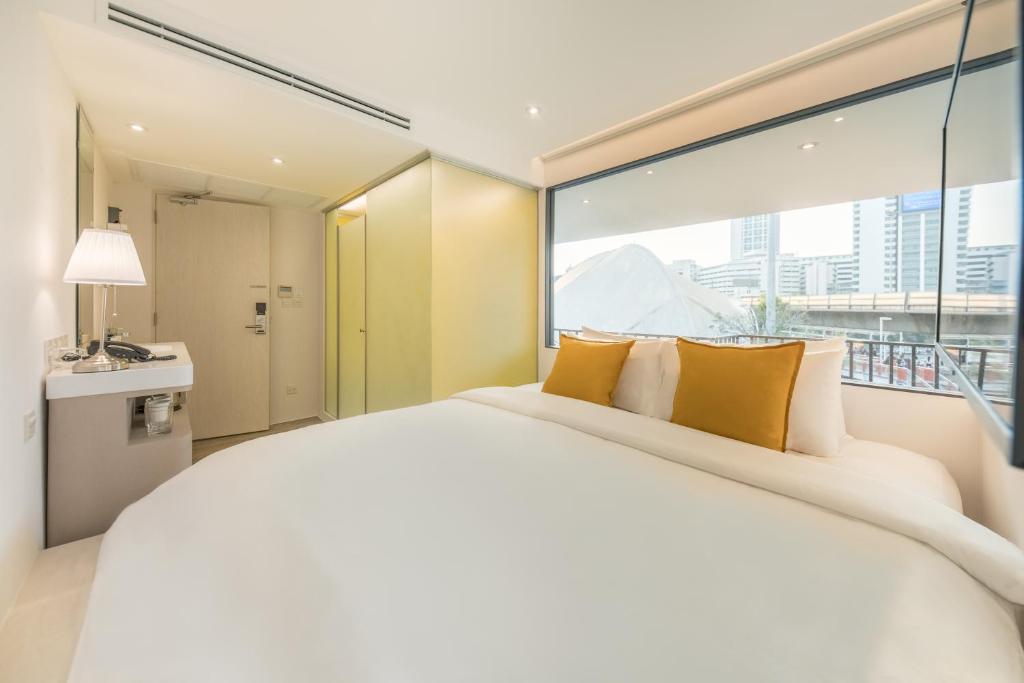 a bedroom with a large white bed with a large window at Yello Rooms Hotel Victory Monument in Bangkok