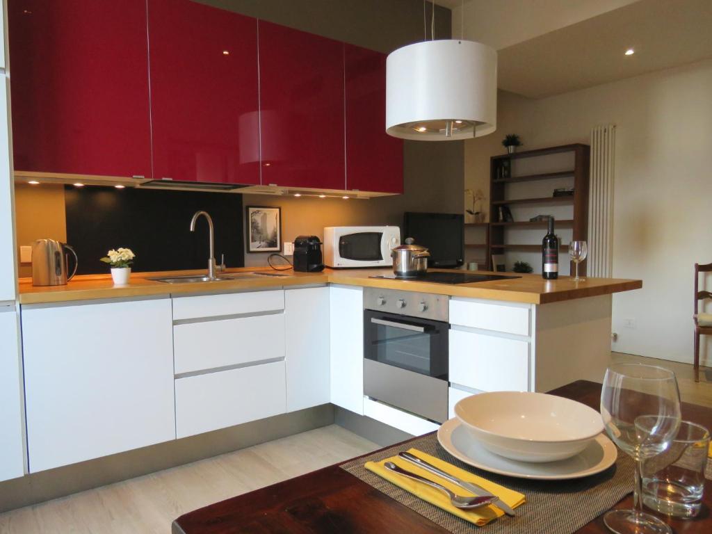 ボローニャにあるSanta Croce Apartmentsの赤いキャビネットとテーブル(皿付)が備わるキッチン