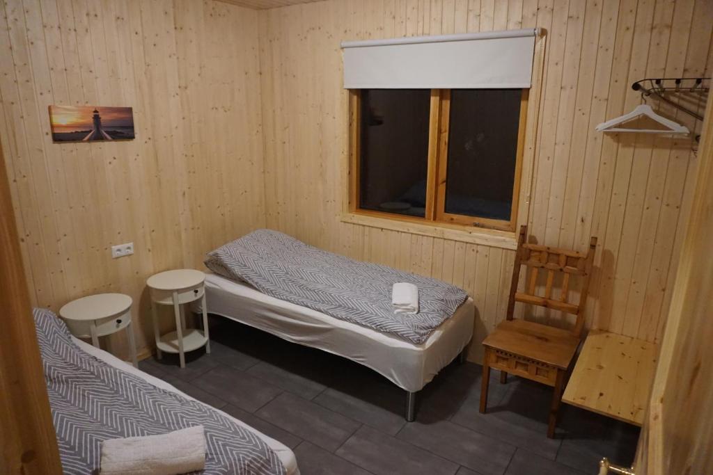 a small room with a bed and a chair and a window at Middalskot Cottages in Laugarvatn