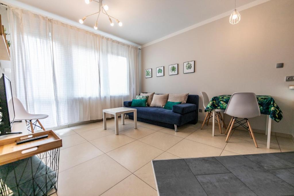 a living room with a blue couch and a table at Victus Apartamenty, Apartament Avocado in Sopot