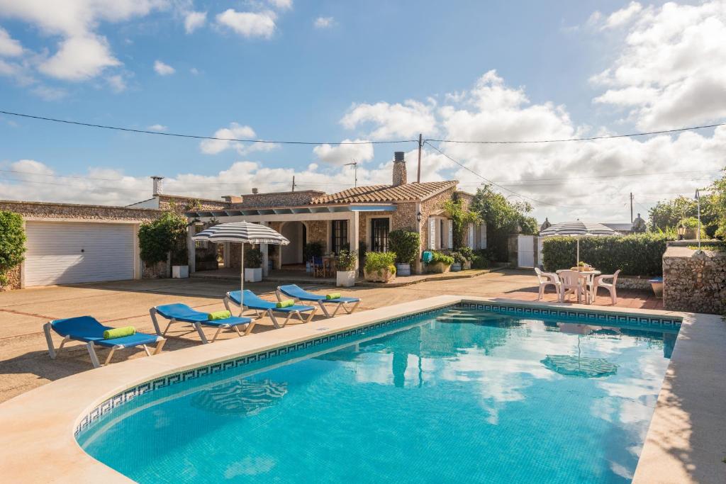 a swimming pool with chairs and a house at Villa Sa Canova by Mauter Villas in Ciutadella