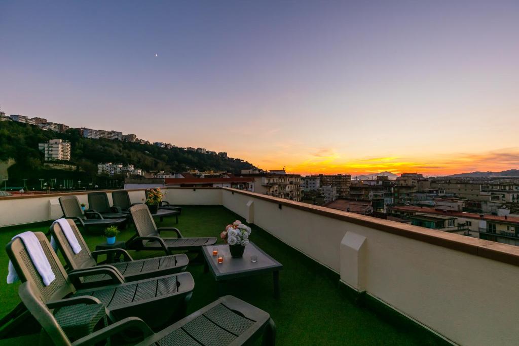 einen Balkon mit Stühlen, Tischen und Sonnenuntergang in der Unterkunft Culture Residence Consalvo Otto in Neapel