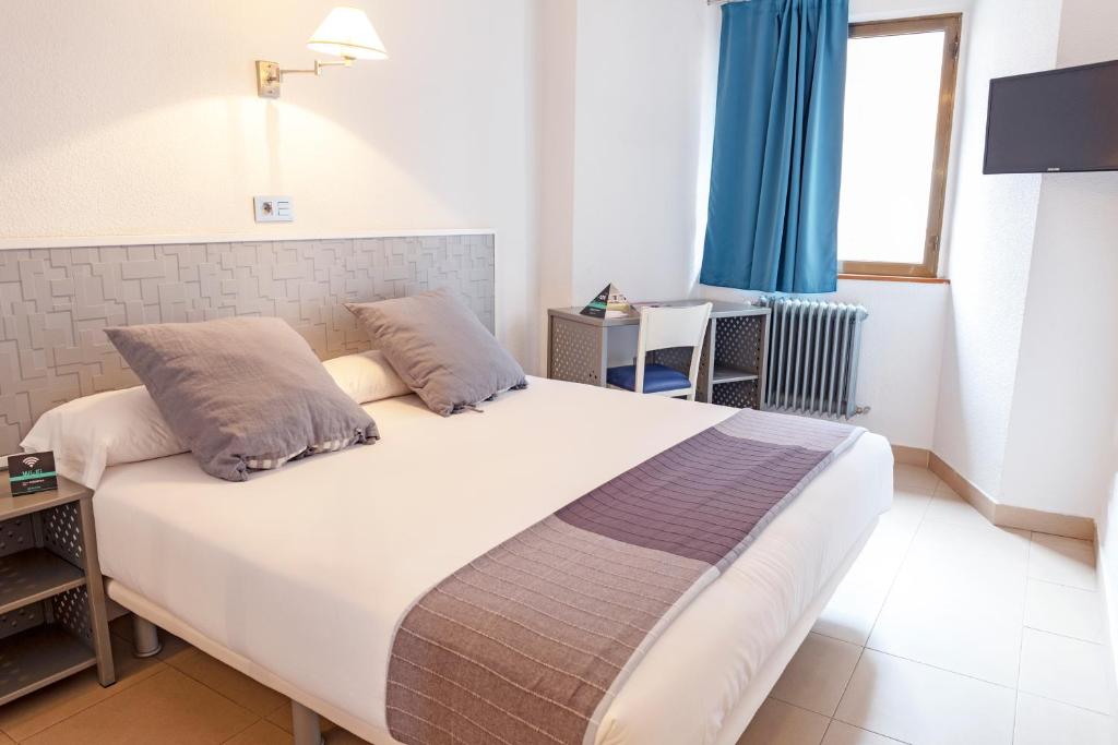 Hotel Alda Centro Palencia في بالينثيا: غرفة نوم بسرير أبيض كبير مع ستائر زرقاء