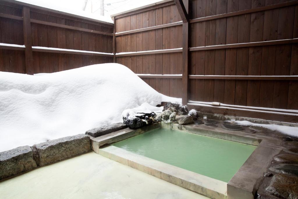 uma piscina de água com neve ao lado de uma cerca em Shiunso em Nikko