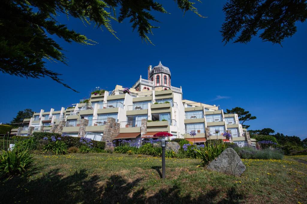 un grand bâtiment blanc avec une tour en haut dans l'établissement Hotel Ker Moor Saint-Quay Portrieux, à Saint-Quay-Portrieux