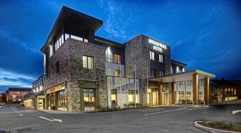 Modern hotel building with stone facade at dusk, featuring a prominent entrance.